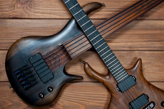 Electric rhythm guitar and five-string bass photographed on a wooden surface.
