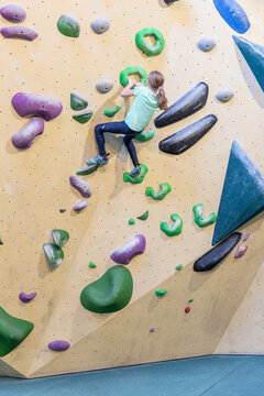Girl climbing on boulder wall