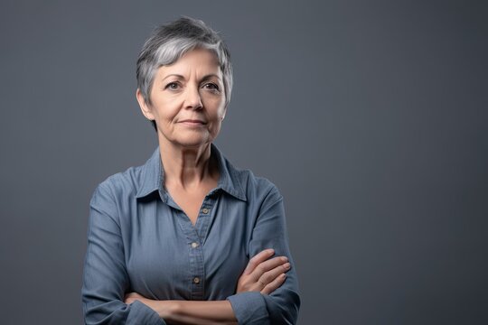 Senior woman confident, arms folded, thoughtful smile, grey background, copy space. Photo generative AI