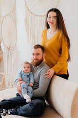 Woman and man holding a newborn. Mom, dad and baby. Close-up. Portrait of young smiling family with newborn on the hands. Happy family on a background.