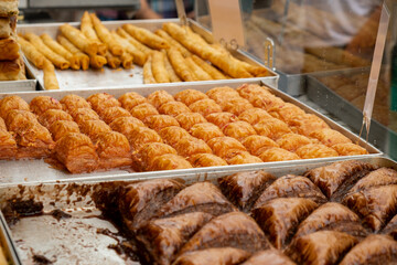 Various types or many colorful assortment of Turkish sweets for sale in street shop food festival. Baklava and pastries are sold on trays on the counter. Travel tourist attraction 