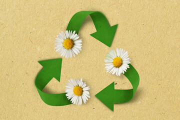 Recycling symbol with daisy on recycled paper background - Concept of ecology and recycling