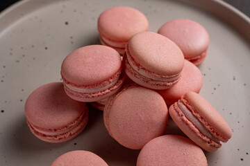 Pink macaroons on a plate on a dark table
