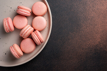 Pink macaroons on a plate on a dark table

