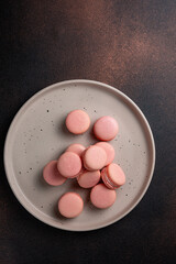 Pink macaroons on a plate on a dark table
