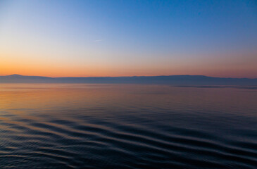 Obraz premium Sea and mountains horizon during sunset at dusk.