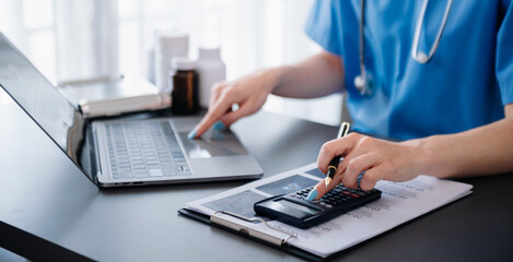 Healthcare costs and fees concept.Hand of smart doctor used a calculator and smartphone, tablet for...