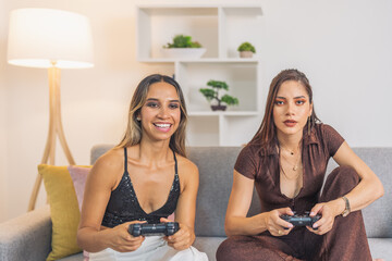 Elegant women playing console sitting on the sofa at home © Guillermo Spelucin