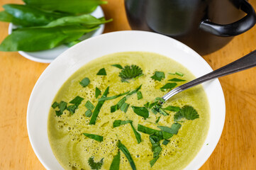 Spring soup from bear garlic and nettle, green leaf, black pot.