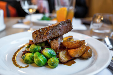 Beefsteak, green brussels sprouts and baked potato , restaurant table.