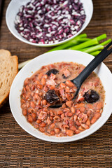 Legume soup from bean and plum, green onion, raw bean and bread.