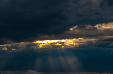Fototapeta premium Beautiful dramatic sky with sunbeams through the clouds at sunset
