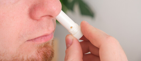 Adult man uses nasal stick inhaler to smell for relieve dizzy and faint symptoms. - obrazy, fototapety, plakaty