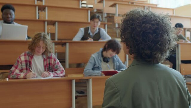 Selective focus shot of modern professor giving lecture to group of gen Z students in university