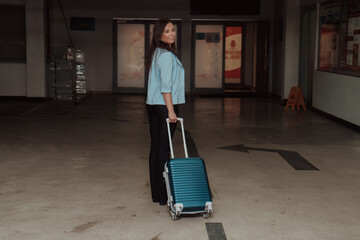 Fototapeta na wymiar A business woman with a suitcase set in a modern garage while going to the airport. Business travel concept