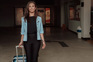 A business woman with a suitcase set in a modern garage while going to the airport. Business travel concept