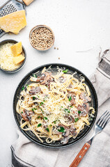 Prepared pasta with mushrooms with parsley and cheese on grey table background, top view. Healthy cooking and eating. Italian food concept