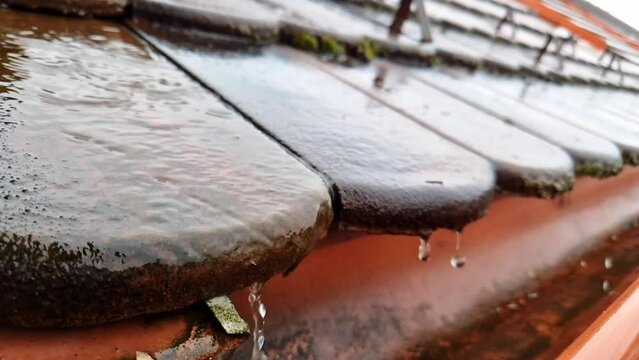 Close up of water falling down to gutter from the roof during heavy rain storm, slow motion footage clip