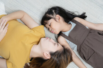 Happy Asian mother lying on the floor with her daughter.