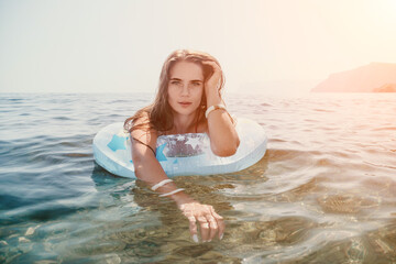 Woman summer sea. Happy woman swimming with inflatable donut on the beach in summer sunny day, surrounded by volcanic mountains. Summer vacation concept.