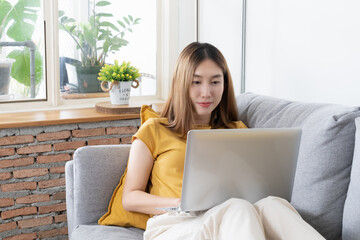 View of Asian women using laptop on sofa in livingroom.