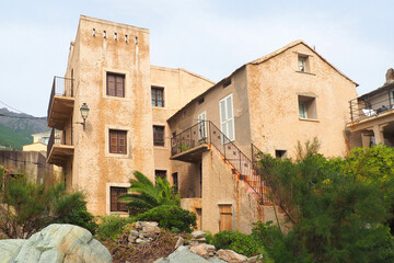 Fototapeta na wymiar One of the charms of the island of Corsica, nicknamed the Island of Beauty, are its narrow streets: ocher, yellow or pink, white houses and small flowered balconies overlooking the cobbled streets