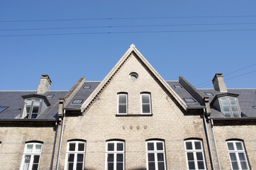 Facade and roof of a historic terraced house with dormer with a clear blue sky in Copenhagen in Denmark