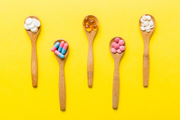Vitamin capsules in a spoon on a colored background. Pills served as a healthy meal. Red soft gel vitamin supplement capsules on spoon