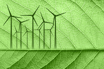 Silhouettes of wind turbines on a leaf background. Green energy concept