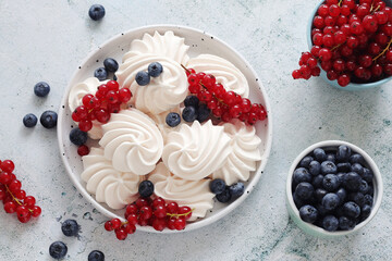 White sweet traditional merenques with berries on the plate	