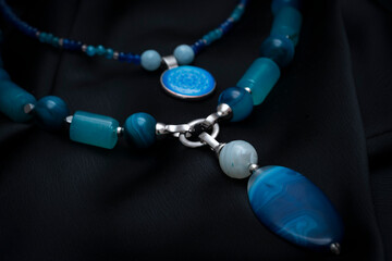 Choker made of natural stones and pendants and epoxy resin. Beads and pendant from agate on a black...