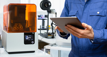 Engineer using digital tablet to program 3d printer