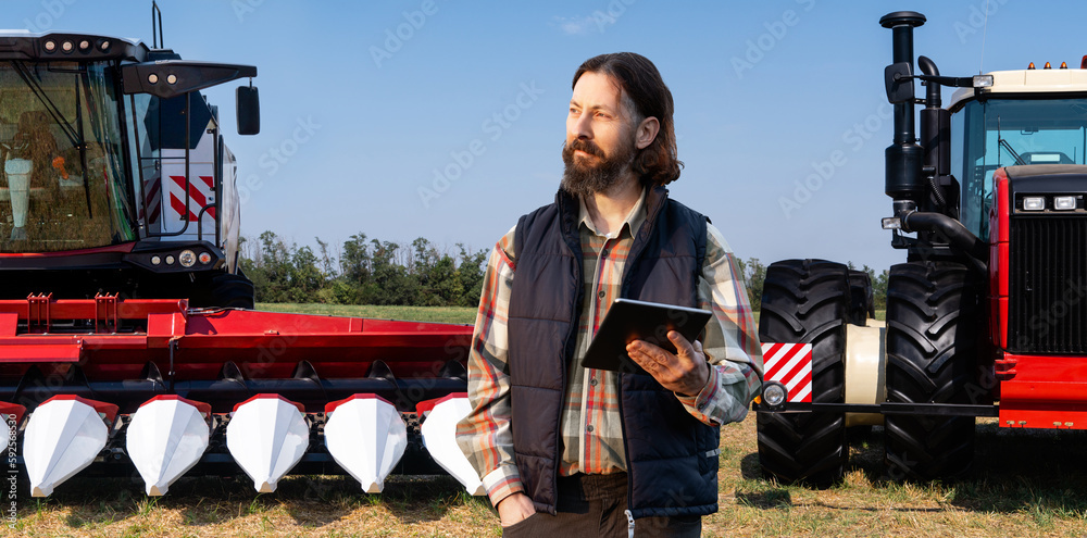 Poster farmer with digital tablet on a background of combine harvester and tractor. smart farming concept.