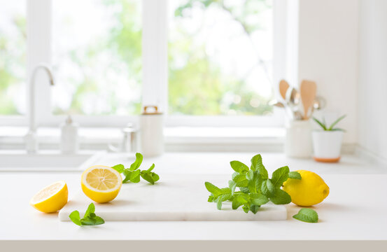 Lemons and mint on marble board over kitchen window background