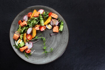 Red fish salad with radish and fresh cucumber. Healthy salad for lunch. A lean dish. Healthy food. Dark background. Vertical photo.Copy space.Flat lay.