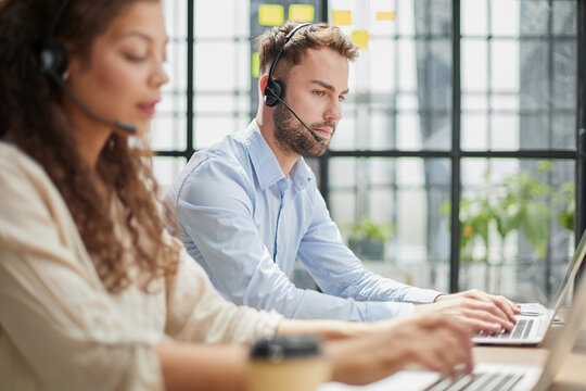 male call-center operator with headphones sitting at modern office