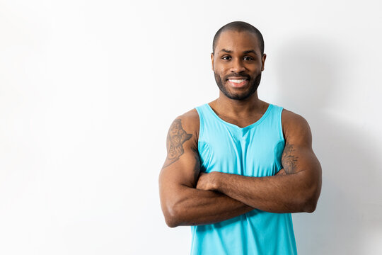 Muscular dark-skinned man poses over a white background in sportswear.The adult poses with arms crossed while looking at the camera.Concept sport in African people.