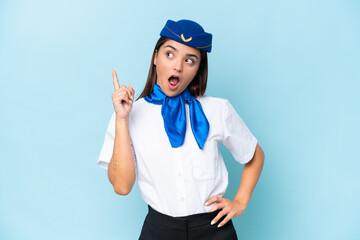 Airplane stewardess caucasian woman isolated on blue background thinking an idea pointing the finger up