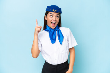 Airplane stewardess caucasian woman isolated on blue background pointing up and surprised
