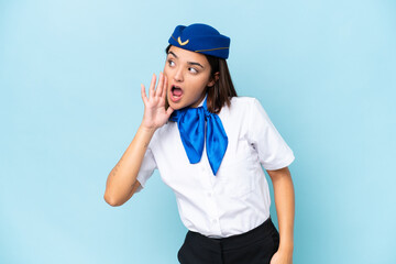 Airplane stewardess caucasian woman isolated on blue background shouting with mouth wide open to the lateral