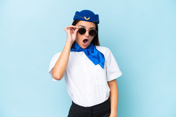 Airplane stewardess caucasian woman isolated on blue background with glasses and surprised