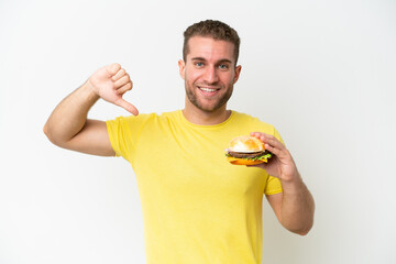 Young caucasian man holding a burger isolated on white background proud and self-satisfied