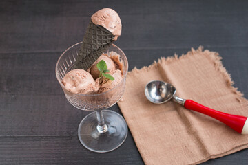 chocolate ice cream in a black waffle cone. Chocolate dessert with cinnamon sticks on a black background