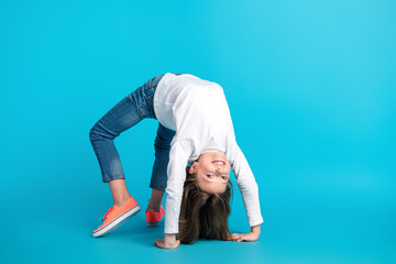 Photo of carefree playful little girl wear white shirt staying upside down emtpy space isolated...