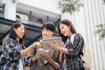 Asian students joining study book, smiling with laptop computer tablet at high school university, college, vacation, summer vacation.
