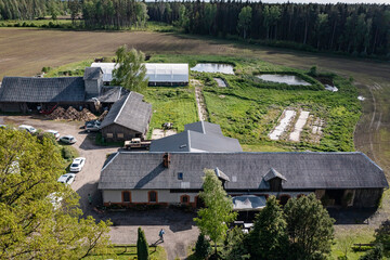 Agricultural buildings captured from a drone in sunny weather during summer, including farmhouses, barns, sheds, silos, stables, greenhouses, orchards, vineyards, fields © Raivo