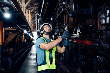 Fototapeta na wymiar Male engineer maintenance locomotive engine wearing safety uniform, helmet and gloves work in locomotive repair garage. 