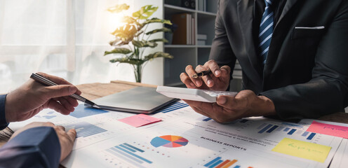 Two business people talk project strategy at office meeting room. Businessman discuss project planning with colleague at modern workplace while having conversation and advice on financial data report