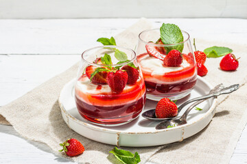 Italian dessert panna cotta in glass with strawberries. Healthy sweet food, hard light, dark shadow