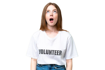 Young volunteer woman over isolated chroma key background looking up and with surprised expression